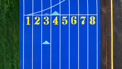 Aerial image of a new blue and yellow eight, 8, lane running track with white lane lines and other markings.	