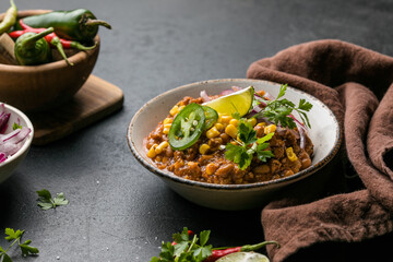 Chili con carne on wooden table with corn and spices