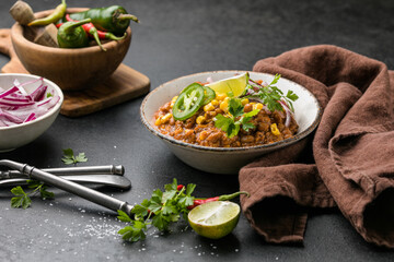 Chili con carne on wooden table with corn and spices