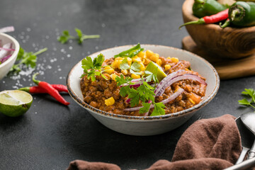 Chili con carne on wooden table with corn and spices