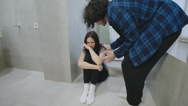 Professional actors portray a violent domestic abuse scene: a man yells and grabs a crying woman by the hair as she sits on the floor, resisting in fear and pain