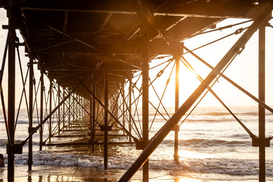 Underside view of the pier structure at sunset in Pimentel, Peru
