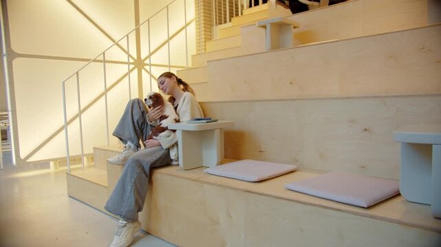Woman relaxing with dog on tiered wooden seating indoors