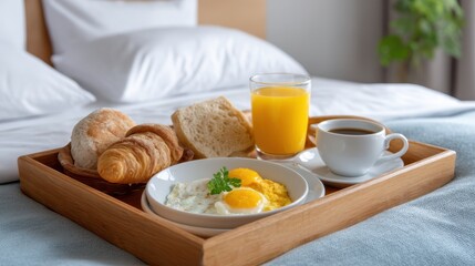 Breakfast Tray in Hotel Room with Fresh Eggs, Pastries, Juice, and Coffee on Bed