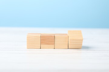 Blank cubes on white wooden table against light blue background