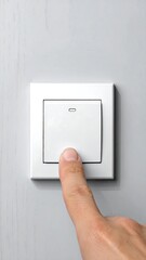 A close-up of a finger pressing a white electrical switch
