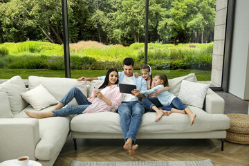 Happy family spending time together on sofa near big window at home