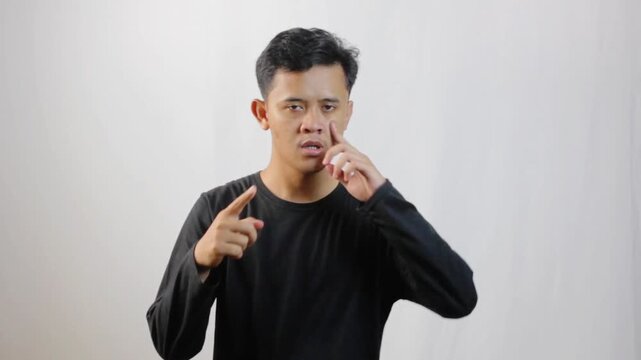Asian man tries to remove saliva from nose by squeezing it with his finger and pushing it out