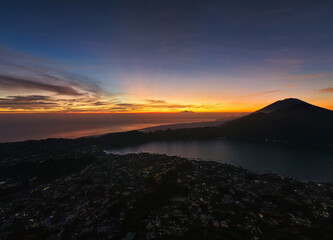 serene sunset over volcanic crater lake with twinkling village lights and reflective water Kintamani Abang Angung Bali