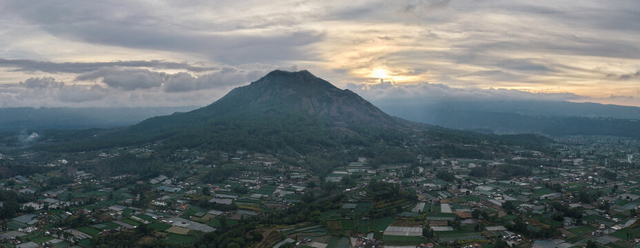 panoramic twilight cityscape view, mountain volcano silhouette with city lights during moody dusk atmosphere Kintamani Bali