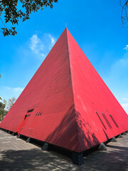 Modern geometric red pyramid building under blue sky