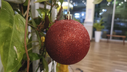 Red bauble glitter ornament holiday decor Christmas tree festive sparkle indoor plant bokeh lights