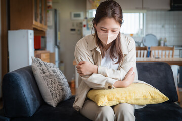 風邪をひいてリビングで寒そうにする女性
A woman who has caught a cold and looks cold in the living room