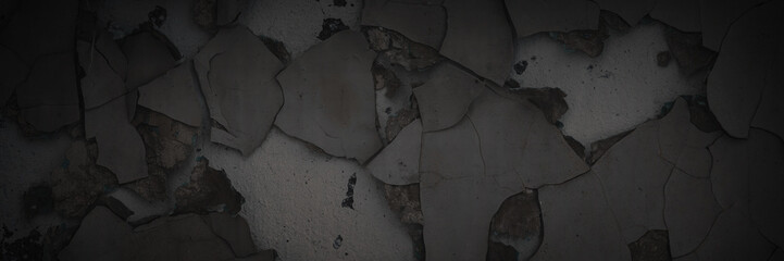 Dark wide panoramic background. Peeling paint on a concrete wall. Dark grunge texture of old cracked flaking paint. Weathered rough painted surface. Patterns of cracks. Darkness background for design.