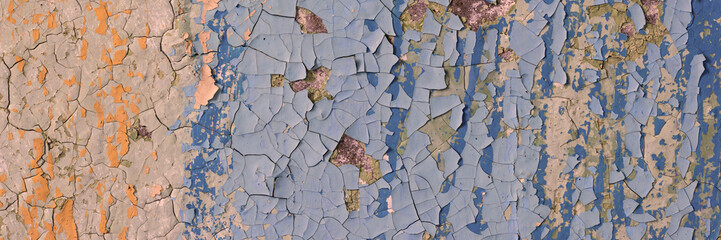 Peeling paint on the wall. Panorama of a concrete wall with old cracked flaking paint. Weathered rough painted surface with patterns of cracks and peeling. Wide panoramic texture for grunge background