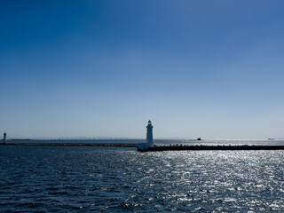 A submarine on the surface of the ocean with sparkling seas and a lighthouse in the foreground