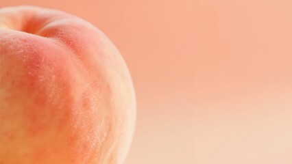 Fototapeta premium Close-up of a ripe peach with soft pink and orange hues against a blurred background