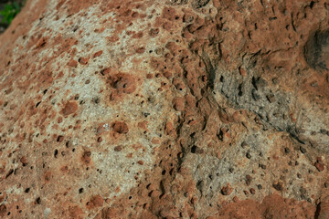 Porous volcanic rock with reddish-gray tone, close-up texture view