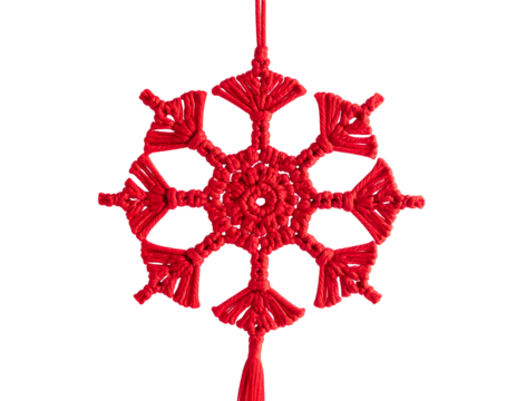 Red macrame snowflake hanging against a black background
