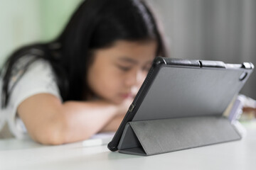 Naklejka premium closeup tablet and smartphone with blur asian child sleep on desk or kid girl bored tired to study online class or learn from home school by computer mobile phone or people studying sleepy on table