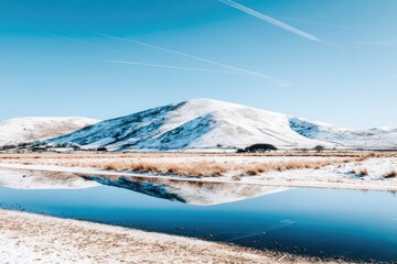 Snow-capped hills reflected in a still blue water