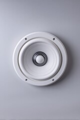 A white ceiling speaker with a white speaker
