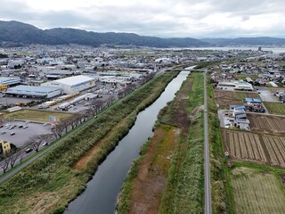 Fototapeta premium A city with a river running through it. The river is surrounded by a green area. The city is full of buildings and cars