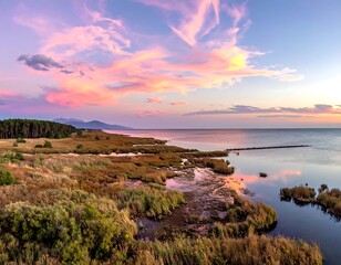 Aerial view of coastal wetlands reflecting sunset hues and dramatic skies