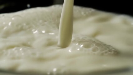 Close-up slow motion shot of fresh white milk being poured into a bowl, creating splashes and bubbles, highlighting the creamy texture and liquid movement for dairy and beverage concepts.