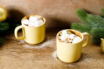 Hot chocolate in yellow cup on wooden table background.