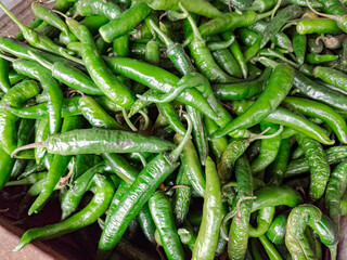 Fresh green chili peppers stacked in bulk. Green chilies for culinary seasoning and flavor. Organic green chilies harvested for spice. Fresh green peppers for sale at the market
