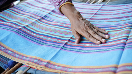 Close up of traditional Indonesian handwoven fabric from West Nusa Tenggara, touched by local...