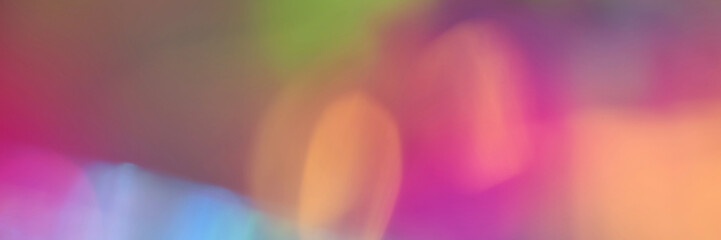 Colorful abstract blurred background in vivid gradient hues of pink, orange, green, and blue.