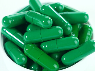 Many green capsules on a white background.