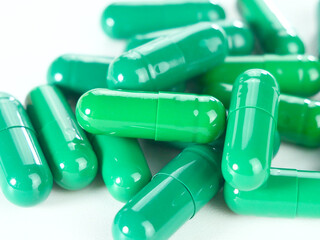 Many green capsules on a white background.