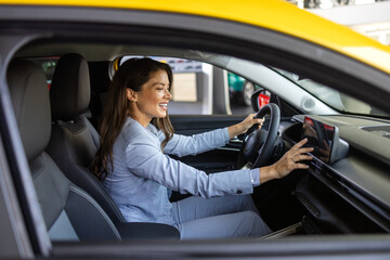 Happy woman in new car. Beautiful girl looking through the car window. Business woman choosing new...