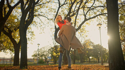 Couple enjoying a sunny autumn day in a park, embracing and laughing together