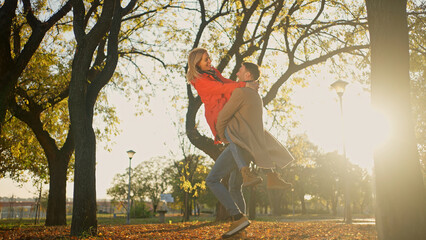 Couple enjoying a sunny autumn day in a park with trees and fallen leaves