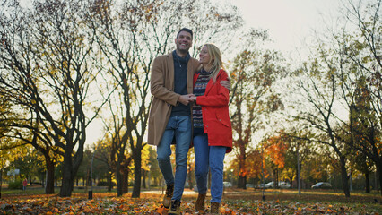 Obraz premium Happy couple walking together in a park during the autumn season