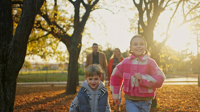 Happy children running in the park with their parents on a sunny autumn day - Powered by Adobe