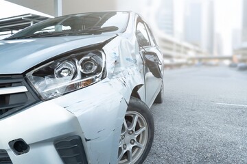 Fototapeta premium Front side view of a car with visible damage and dents after an accident. Vehicle crash, insurance claim, road safety, and car repair concept.