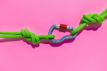rope with a secure knot and a carabiner lies on a colored background. Equipment for rock climbing and mountaineering. reliable connection. concept of reliability and strength. © zhukovvvlad
