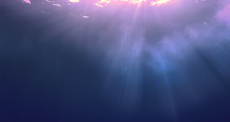 Underwater photo of rays of sunlight coming through the surface of the blue ocean. Abstract backgrounds.