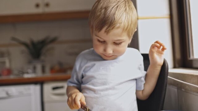 Little blond boy slicing fresh mango