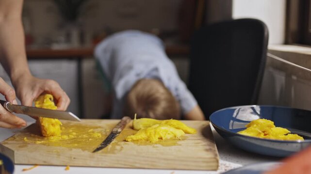 Mother slicing fresh mango for her son