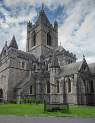 Christ Church Cathedral in Dublin with its Gothic architecture, arched windows, and central tower, set against a partly cloudy sky with a grassy area