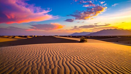Fototapeta premium Vibrant sunset over a vast desert landscape with rippling sand dunes and distant mountains