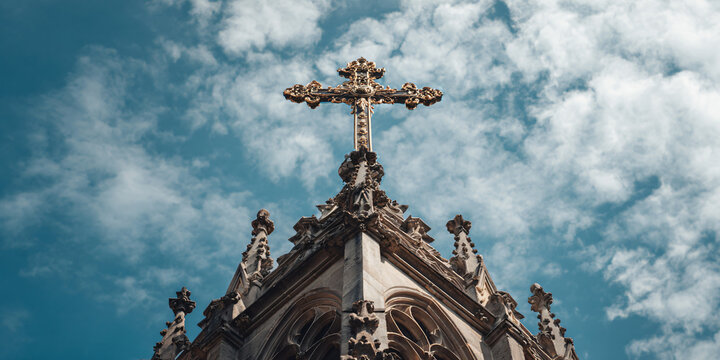 Gothic Church Spire with Ornate Cross Against a Dramatic Sky Architectural Detail of a Stone Carved Cross on a Medieval Cathedral Tower