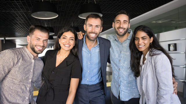 Fototapeta Group portrait happy smiling multiethnic businesspeople hugging looking at camera
