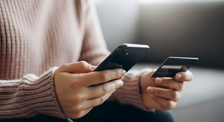 Closeup of a person holding a smartphone and a credit card, ready to make an online purchase